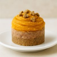 A mini cake designed for cats, placed on a white plate with simple decoration.